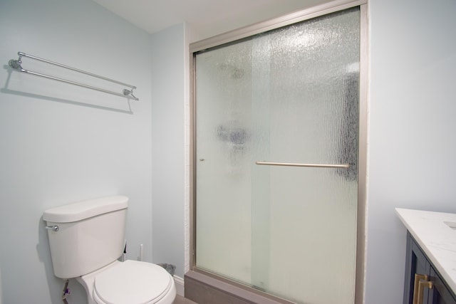 bathroom with a shower with shower door, toilet, and vanity