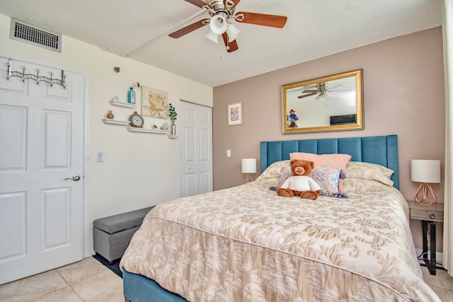 tiled bedroom with ceiling fan, a closet, and a textured ceiling