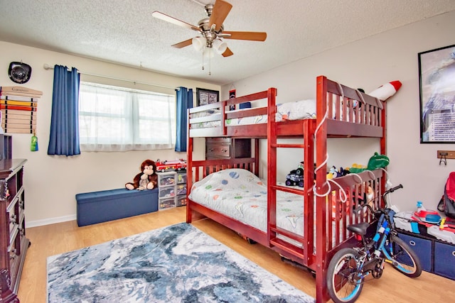 bedroom with ceiling fan, light wood-type flooring, and a textured ceiling