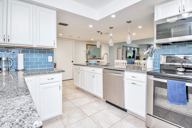 kitchen with white cabinets, tasteful backsplash, decorative light fixtures, and stainless steel appliances