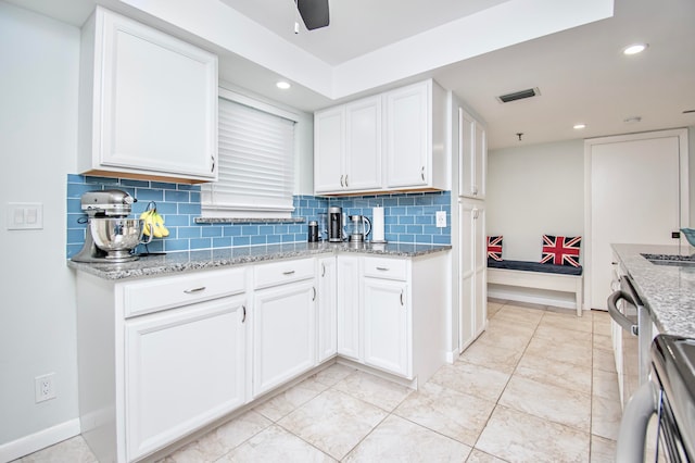 kitchen featuring backsplash, light stone counters, white cabinetry, and light tile patterned floors