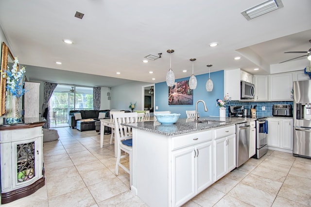 kitchen featuring sink, appliances with stainless steel finishes, light stone counters, ceiling fan, and kitchen peninsula