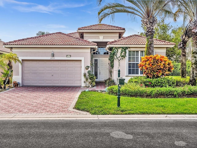 mediterranean / spanish-style home featuring stucco siding, decorative driveway, and an attached garage