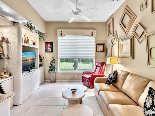 living room featuring light tile patterned flooring, a textured ceiling, baseboards, and a ceiling fan