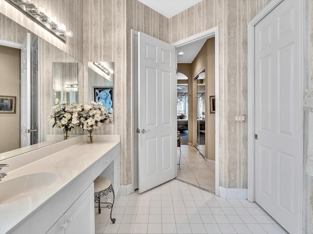 ensuite bathroom featuring tile patterned floors, baseboards, and wallpapered walls