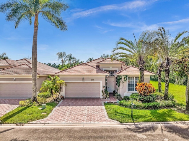 mediterranean / spanish-style house with a front lawn, decorative driveway, a garage, and stucco siding