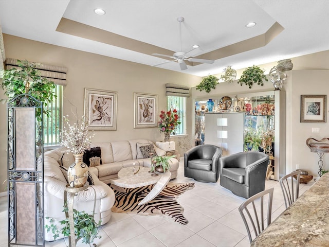 tiled living room featuring a raised ceiling and ceiling fan