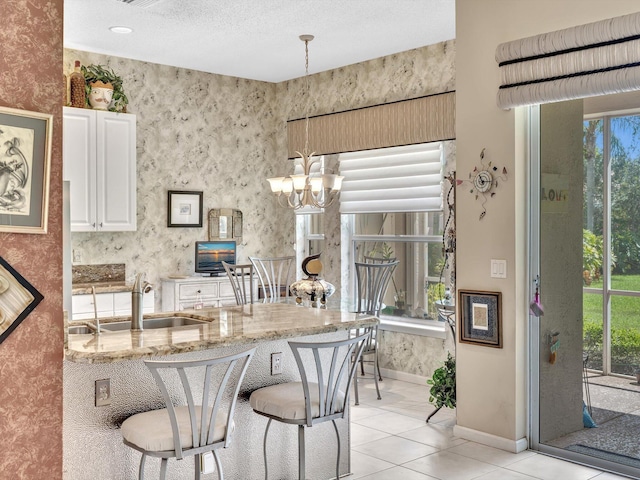 kitchen featuring a wealth of natural light, a breakfast bar area, light stone counters, and a sink