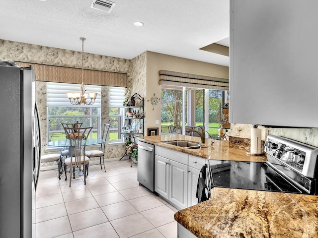 kitchen featuring visible vents, a sink, a textured ceiling, appliances with stainless steel finishes, and an inviting chandelier