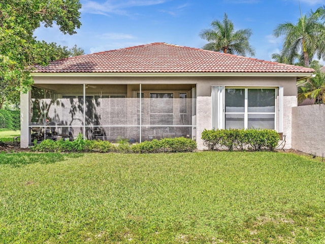 rear view of property with stucco siding, a lawn, and a sunroom