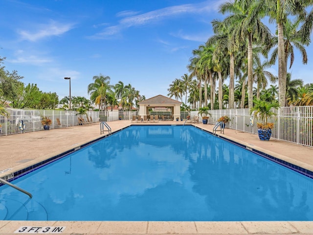 community pool with a gazebo, a patio area, and fence