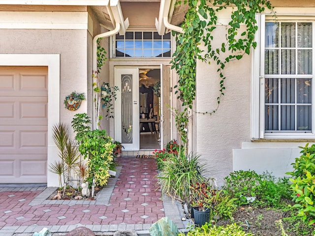 doorway to property with stucco siding and an attached garage