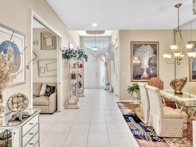 corridor with light tile patterned floors, a notable chandelier, and baseboards