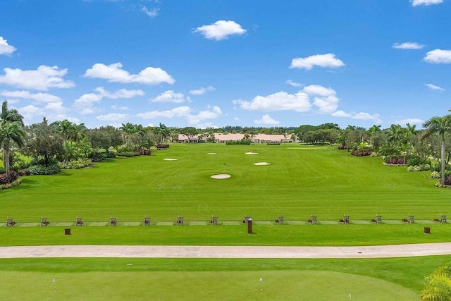 view of property's community featuring view of golf course and a lawn