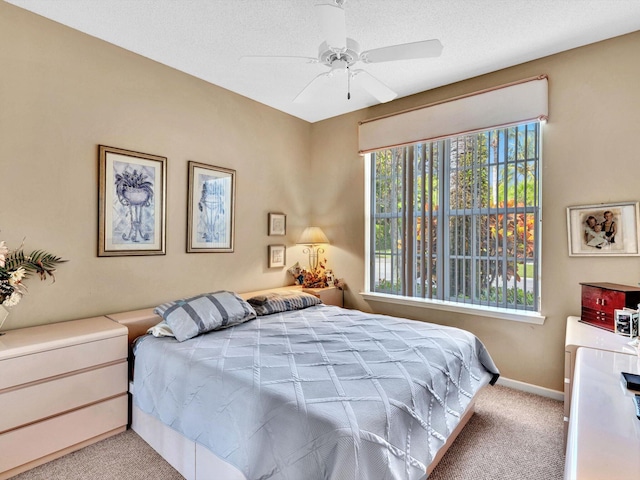 carpeted bedroom featuring a textured ceiling, baseboards, and a ceiling fan