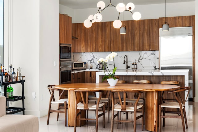 kitchen with tasteful backsplash, hanging light fixtures, light tile patterned floors, and built in appliances