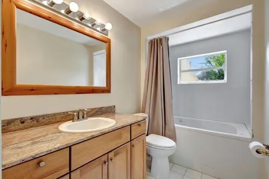 full bathroom featuring vanity, tile patterned floors, toilet, and shower / bath combo with shower curtain