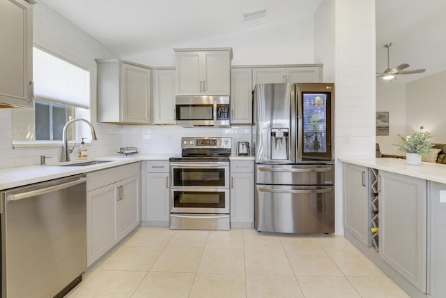 kitchen with lofted ceiling, stainless steel appliances, a sink, visible vents, and decorative backsplash