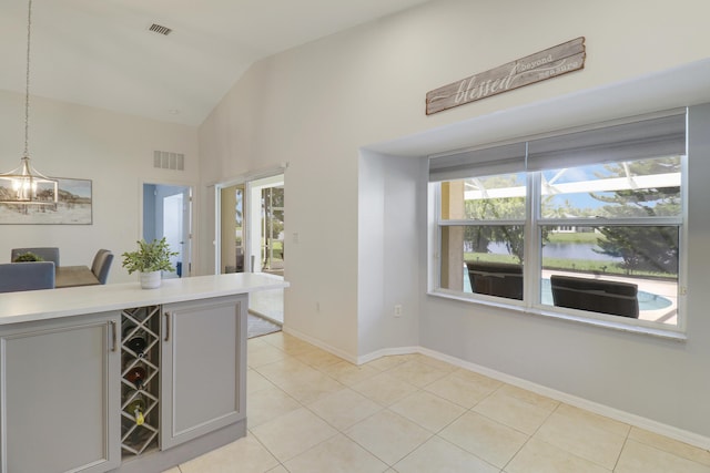 kitchen with gray cabinets, visible vents, vaulted ceiling, and light tile patterned floors