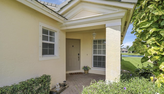 entrance to property with a yard and stucco siding