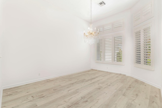 unfurnished room featuring light hardwood / wood-style floors and an inviting chandelier