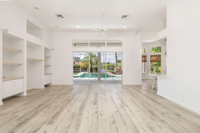 unfurnished living room with light hardwood / wood-style flooring, ceiling fan, built in features, and plenty of natural light