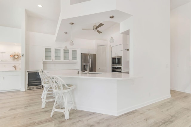 kitchen with light hardwood / wood-style floors, stainless steel appliances, wine cooler, and white cabinets