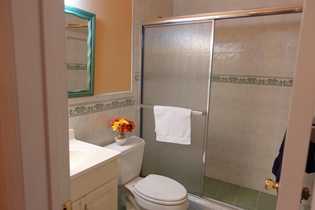 bathroom with toilet, an enclosed shower, vanity, and tile walls