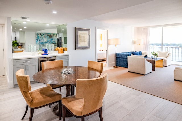 dining area with beverage cooler and light hardwood / wood-style floors