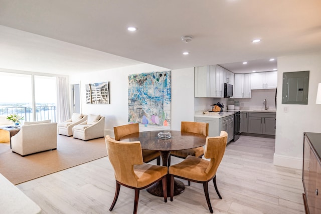 dining room featuring light hardwood / wood-style flooring, electric panel, and sink