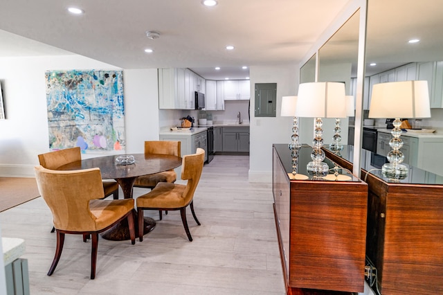 dining space featuring light hardwood / wood-style floors, electric panel, and sink