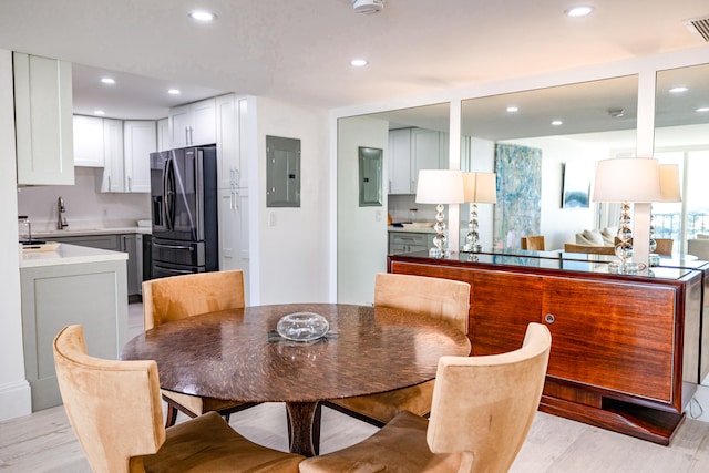 dining space featuring light wood-type flooring, electric panel, and sink