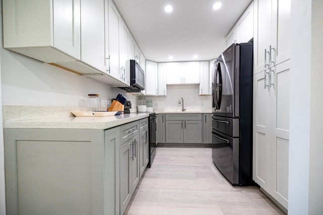 kitchen with light hardwood / wood-style flooring, black appliances, gray cabinets, and sink