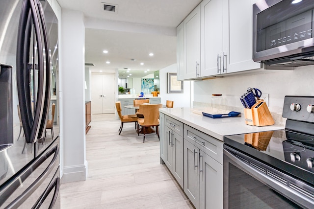 kitchen featuring gray cabinetry, light hardwood / wood-style floors, and stainless steel appliances