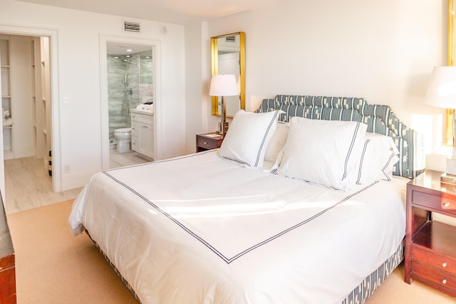 bedroom featuring light hardwood / wood-style flooring and connected bathroom