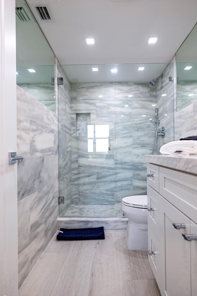 bathroom featuring tile walls, an enclosed shower, vanity, and toilet