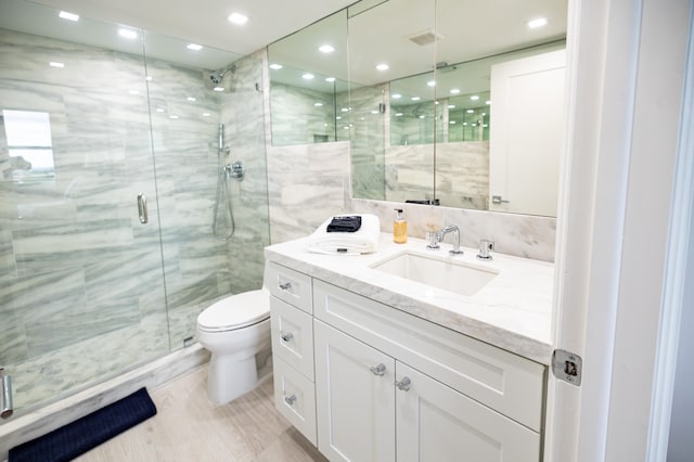 bathroom with walk in shower, vanity, and toilet