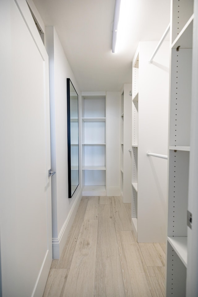 walk in closet with light hardwood / wood-style floors