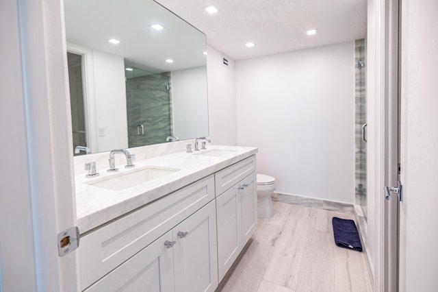 bathroom featuring hardwood / wood-style floors, vanity, toilet, and a shower with door