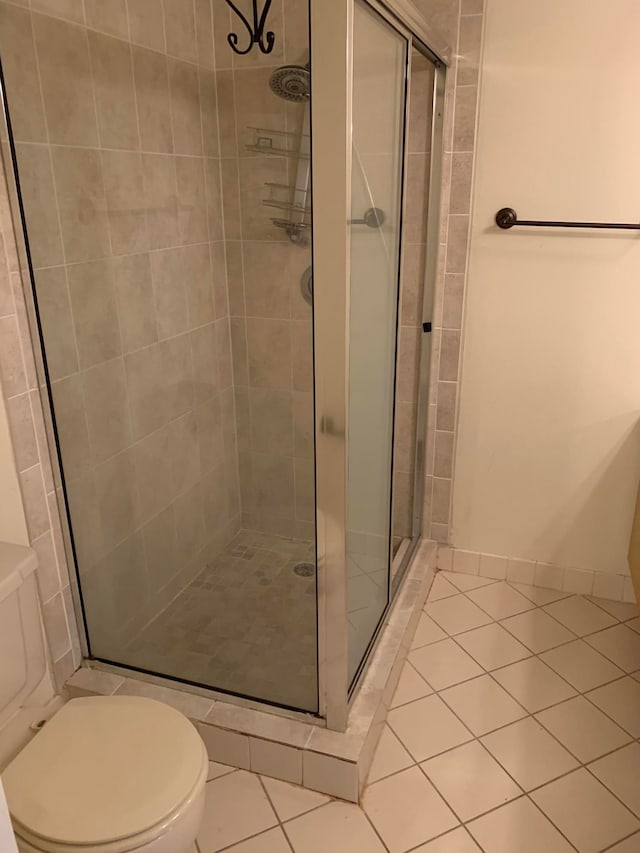 bathroom with a shower with shower door, toilet, and tile patterned flooring