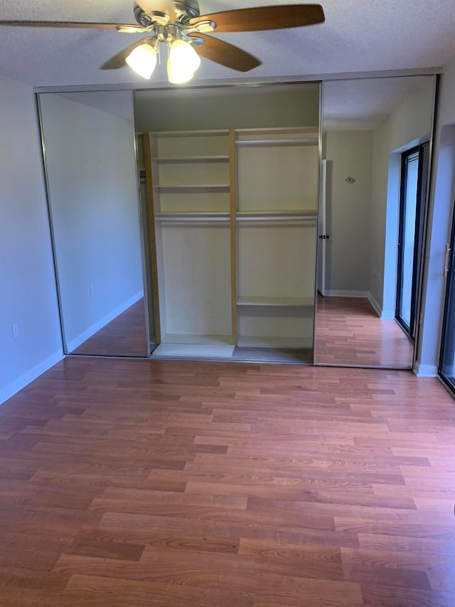 unfurnished bedroom with a textured ceiling, a closet, ceiling fan, and hardwood / wood-style flooring