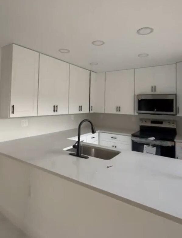 kitchen featuring sink, white cabinets, kitchen peninsula, and electric range oven