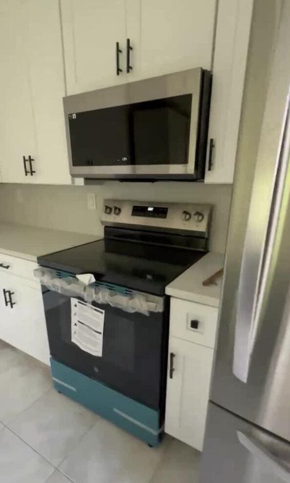 kitchen featuring light tile patterned floors, white cabinetry, and stainless steel appliances