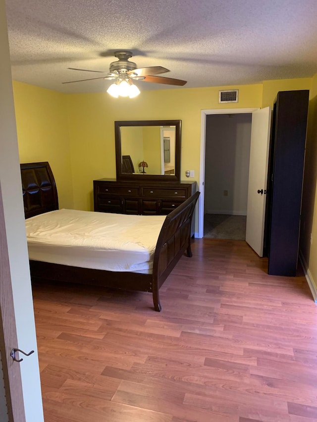 bedroom with a textured ceiling, ceiling fan, and wood-type flooring