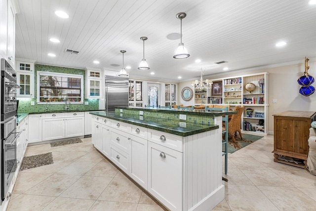 kitchen with pendant lighting, a kitchen island, stainless steel appliances, and white cabinetry