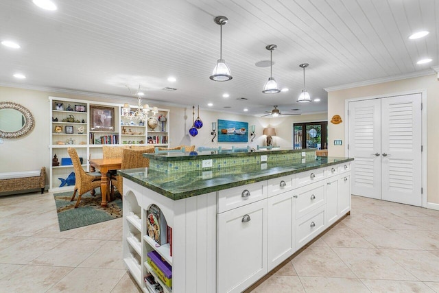 kitchen with white cabinets, a center island, decorative light fixtures, light tile patterned flooring, and ornamental molding