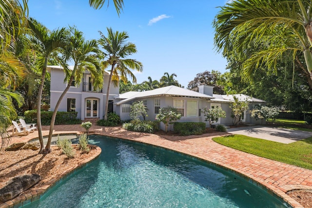 920 Hibiscus Ln, Delray Beach, FL 33444 - rear view of house featuring concrete driveway, an outdoor pool, a patio, and stucco siding