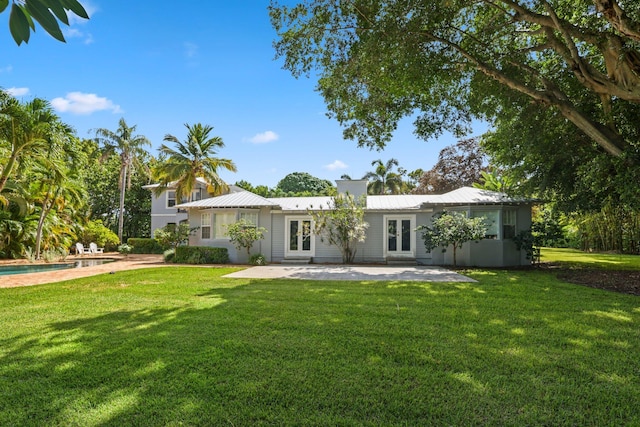 920 Hibiscus Ln, Delray Beach, FL 33444 - rear view of property featuring metal roof, a patio, a yard, and an outdoor pool