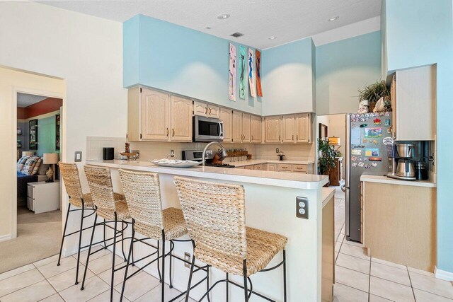 kitchen with kitchen peninsula, stainless steel appliances, and a breakfast bar area