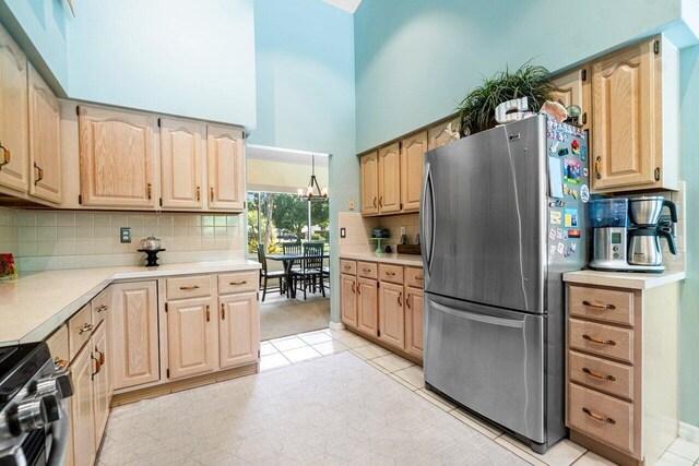 kitchen with electric stove, stainless steel fridge, an inviting chandelier, and light brown cabinets